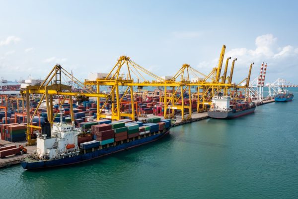 Containers ship and shipping ports cargo logistic freight load unloading by crane forwarding industry import export international worldwide, business services transportation of goods in ocean waters Asia Pacific and Europe photograph aerial view from drone